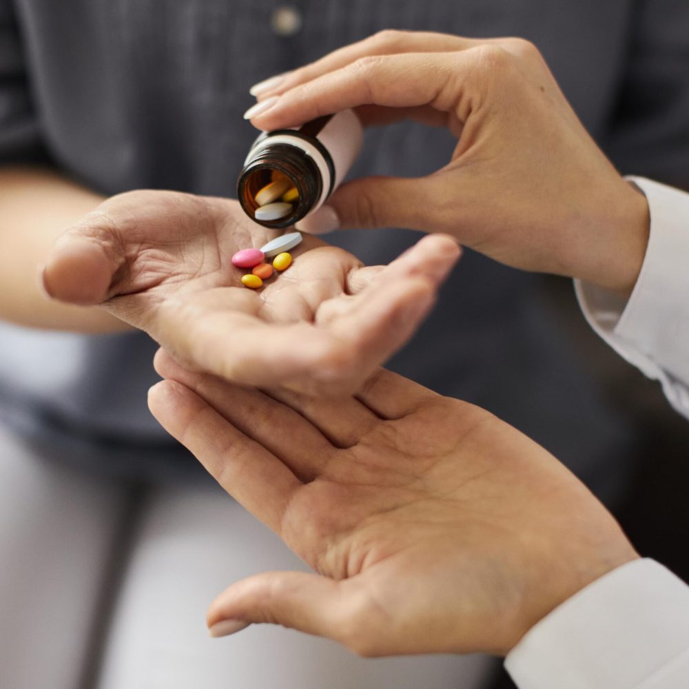 covid-recovery-center-female-doctor-giving-elder-patient-pills-from-bottle-hand